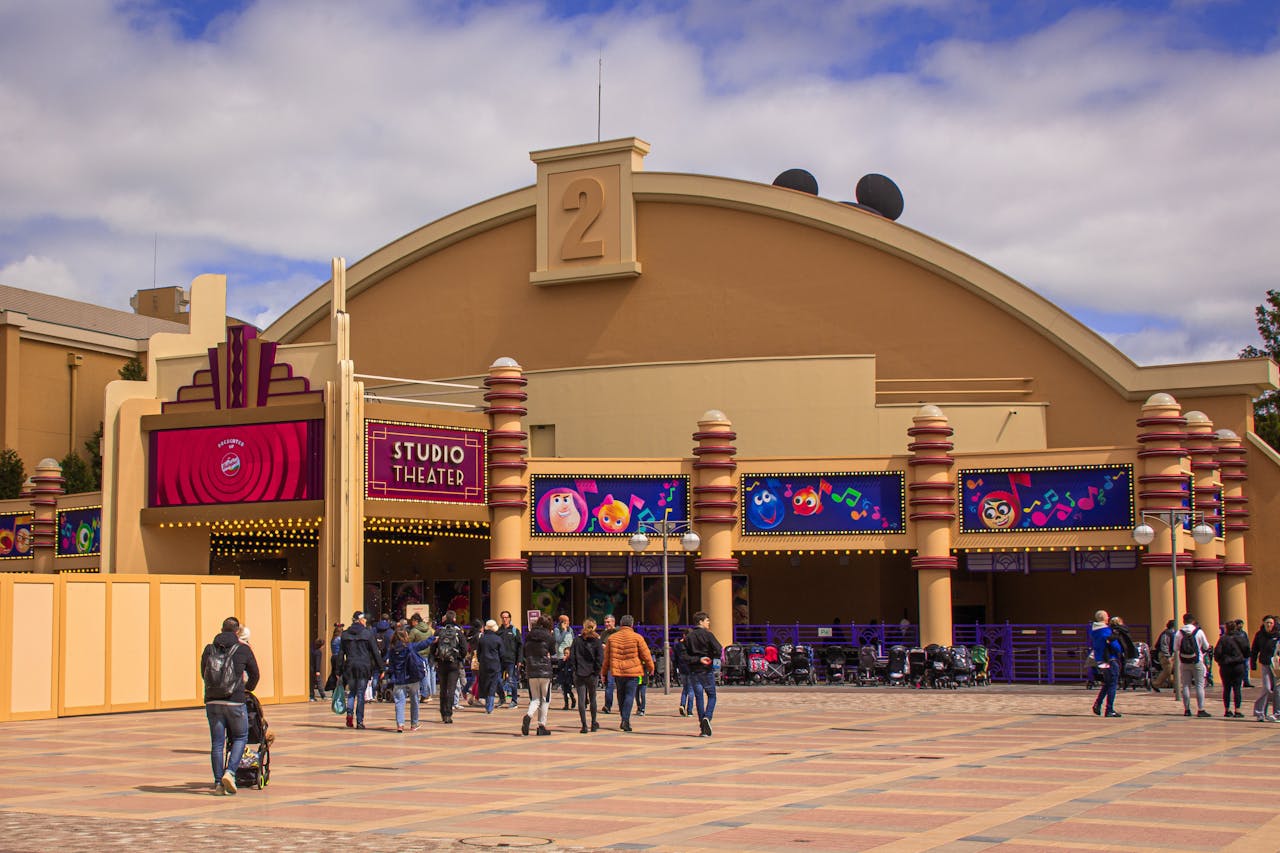 Visitors enter the vibrant Studio Theater entrance at Disneyland Paris on a sunny day.